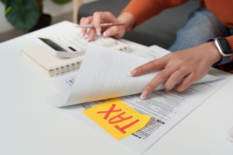A freelancer preparing tax paperwork with a calculator and financial documents on a desk